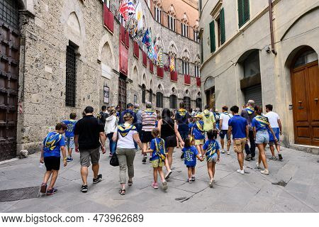 Siena, Italy - August 15 2022: Members Of The Tartuca Or Tortoise Contrada Walking On Via Di Citta I