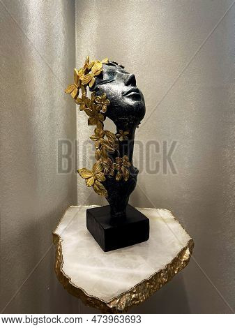 A Beautiful Carved Antique Silver Face With Gold Flower And Butterfly Embellishments Rests On A Marb
