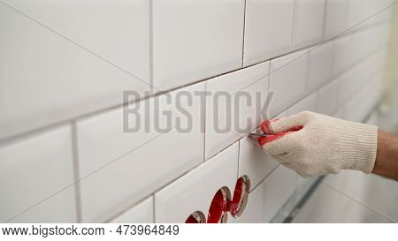 Cleaning The Seams Of Ceramic Tiles. Seams Between Tiles In The Kitchen. A Man Uses A Knife To Remov