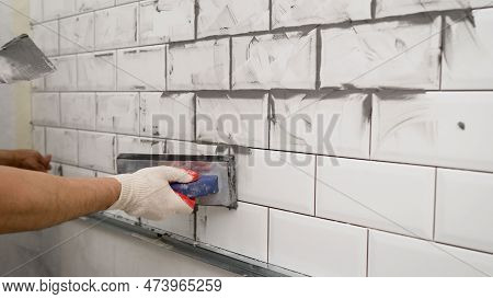 White Tile In The Kitchen With Gray Grout. The Process Of Applying Grout To Ceramic Tiles. Small Cer