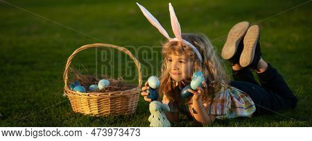 Child With Easter Eggs In Basket Outdoor. Boy Laying On Grass In Park. Easter Egg Hunt. Fynny Kids P