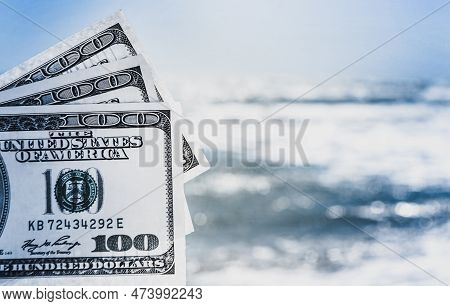 Girl Holding Money Bill Of 300 Dollars On Background Of Sea Ocean Waves And Blue Sky Close-up. Hand 