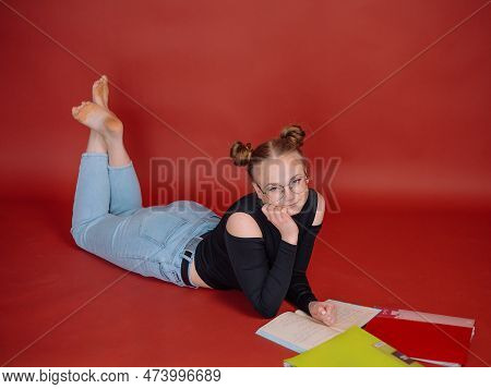 A Young Woman In A Black Blouse With A Bun Hairstyle Holds Notebooks And Folders On A Red Background