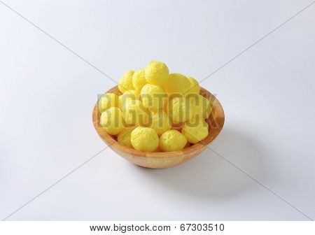 portion of yellow corn puffs in the wooden bowl