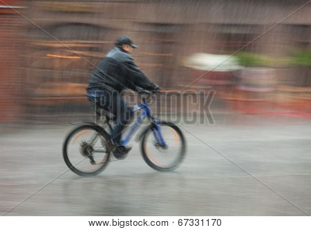 Cyclist Rides Through The Streets On A Rainy Day