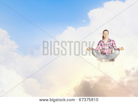 Young woman sitting on chair and meditating