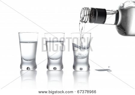 Bottle And Glasses Of Vodka Poured Into A Glass Isolated On Whit