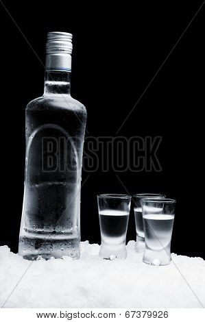 Bottle Of Vodka With Glasses Standing On Ice On Black Background