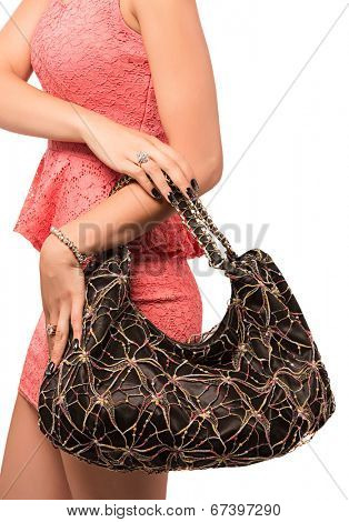 Closeup of woman with embroidered lace black evening bag. Wearing mini lace dress. Isolated on the white studio background.