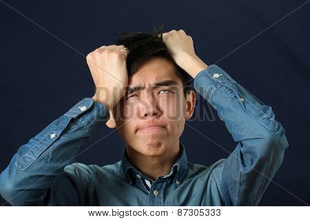 Disappointed young Asian man making face and rolling eyes up