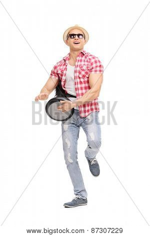 Full length portrait of a young joyful man playing on a doumbek and dancing isolated on white background