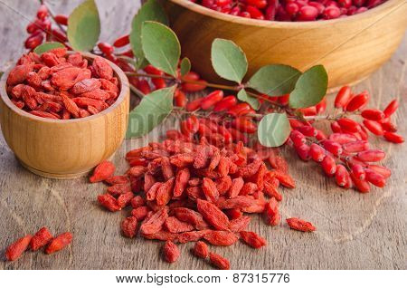 Barberry And Dry Goji Berries In Bowls On Wooden Background