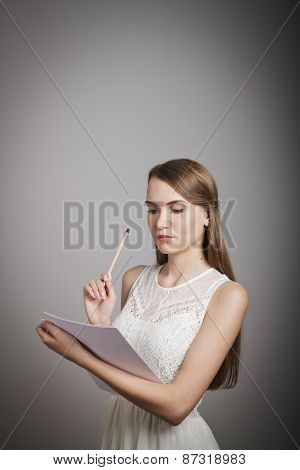 Girl in white with blank paper and a pen in hand.