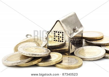Real Estade Background, Little House In A Heap Of Coins Isolated On White