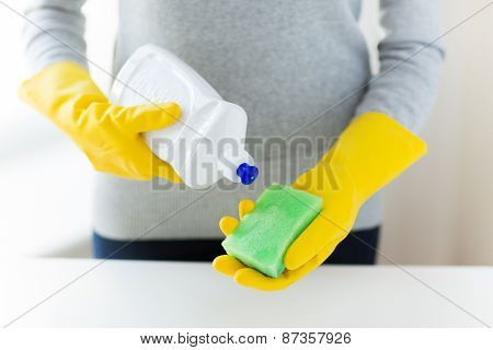 people, housework, washing-up and housekeeping concept - close up of woman applying liquid soap from cleanser bottle to sponge at home