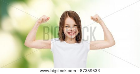 advertising, childhood, gesture, ecology and people - smiling little girl in white blank t-shirt with raised arms over green background