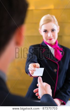 Man in Hotel check in at reception or front office being given key card