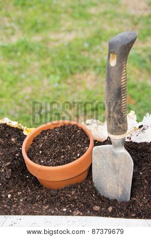 Ceramic pot and a trowel in a bag of topsoil, concept of start of gardening and planting season