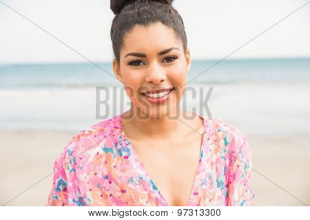 Stylish woman smiling at camera at the beach