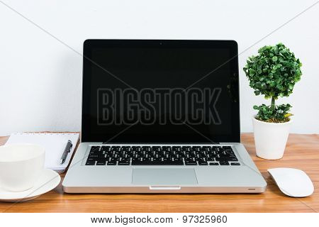 Laptop And Flower Pot On Wooden Table