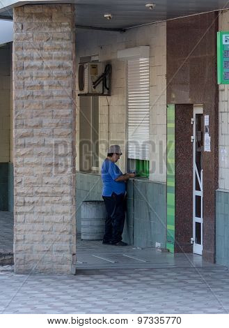 Makeevka, Ukraine - July 30, 2015: Elderly Woman Near An Atm At The Branch Of The Non-working Commer
