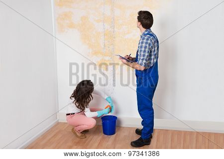 Worker Writing On Clipboard While Woman Squeezing Cloth