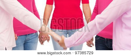 healthcare, people, breast cancer awareness and medicine concept - close up of women in pink shirts holding hands over white background