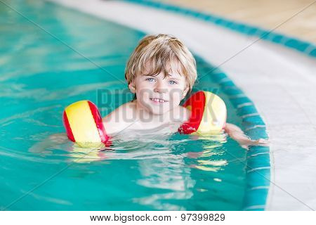 Little Kid Boy With Swimmies Learning To Swim In An Indoor Pool