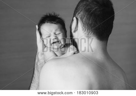 Newborn baby and dad. Baby boy crying on his father shoulder. black and white photo