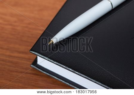 Black Diary, Or Sketchbook With Pen And Pencil On Th Table