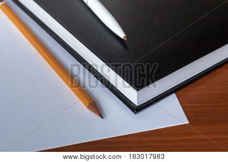 Black Diary, Or Sketchbook With Pen And Pencil On Th Table