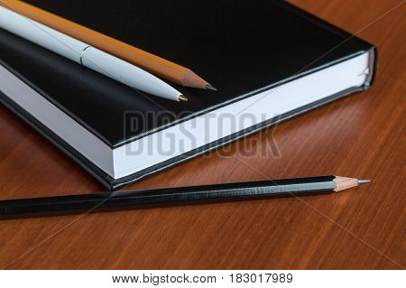 Black Diary, Or Sketchbook With Pen And Pencil On Th Table