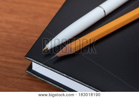 Black Diary, Or Sketchbook With Pen And Pencil On Th Table