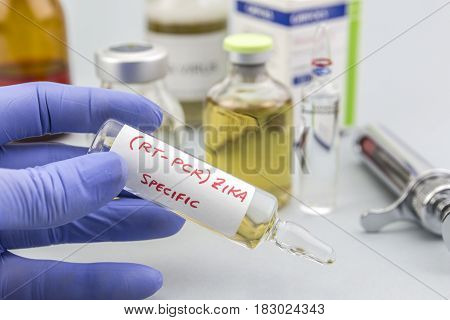 Scientist with blue latex gloves holds vials of ZIKA virus in laboratory for analysis