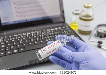 Scientist with blue latex gloves holds vials of ZIKA virus in laboratory for analysis