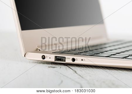 Detail on connectors ultra-thin notebook. The gold notebook on the desk the open notebook lies on a wooden background. Power socket headphone jack