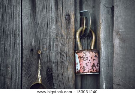 Old padlock on the old rural door. Old grey wood background.
