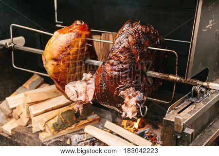 Large chunks of delicious pork hams cooked on an open fire. The street food. Food outdoors. Camping and cooking on a spit over the fire. Camping.