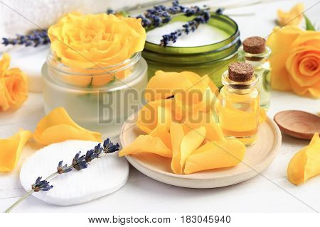 Essential oil blend of rose and lavender, bottles and bright flower petals, fragrant beauty treatment botanical product.