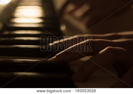 Close-up soft focused atmospheric photography of a hand playing the piano keys. Concept: Music creating, composing, lyrics, performance