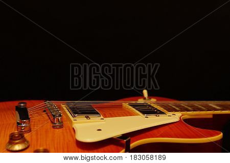 Solid body electric guitar closeup on the black background with plenty of copy space. Selective focus.