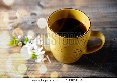 Coffee cup and flowers on garden table with dold bokeh.