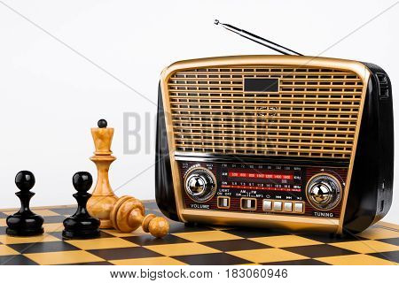 modern retro styled radio receiver with chess pieces on chessboard and white background