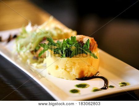 Tasty potatoes with chicken schnitzel and greens on a white plate