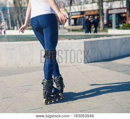 young Roller Girl is learning how to skate. First time on roller skates. View from back