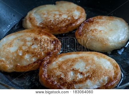 Pancakes fried in oil on fry pan.