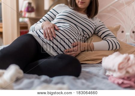 Pregnancy Woman sitting on sofa at home in bedroom