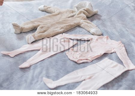 Baby's clothes laid out on bed, natural light