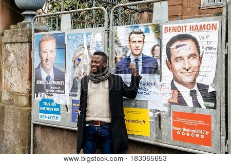 STRASBOURG FRANCE - APR 23 2017: Black ethnicity man showing his support to Emmanuel Macron near all 11 presidential posters