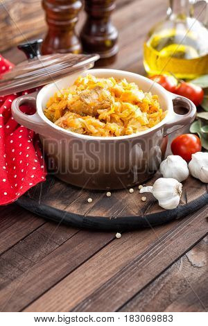 Stewed cabbage with meat on dark rustic wooden background